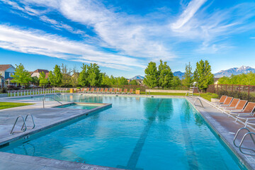 Large public pool surrounded by lounge chairs and wire fence at Daybreak, Utah