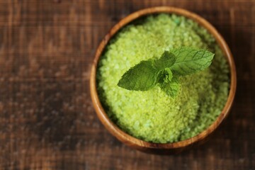 cosmetics salt with Peppermint extract.green salt in a round wooden bowl and sprigs of peppermint on a wooden table. Natural cosmetics and aromatherapy.Organic natural cosmetics for body 