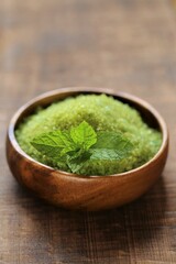 cosmetics salt with Peppermint extract.green sea salt in a round bowl and sprigs of peppermint on a wooden table. Natural cosmetics and aromatherapy.Organic natural cosmetics for body 