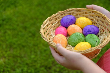 Easter Egg Hunt. Easter eggs set in a basket in children's hands on green grass background. Collecting eggs. Religious tradition. Colorful easter eggs.Easter holiday symbol