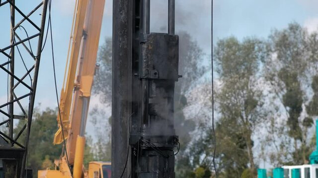 Pile-driving (copra) part of the excavator in close-up. Pile driving works at the construction site. Modern hydraulic lifting mechanisms.