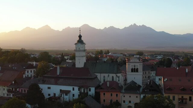 Rotating cinematic drone shot of Church of St. Egidius in Poprad, Slovakia during golden hour with the High Tatras mountains in the background