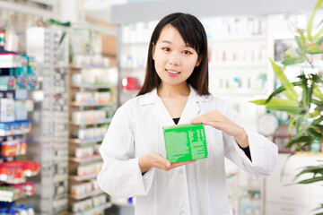 Portrait of positive chinese female pharmacist demonstrating assortment of pharmacy