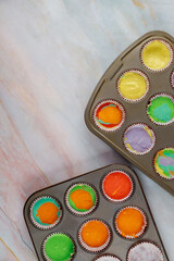 Uncooked rainbow cupcakes on oven tray. Top view.