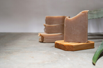 Detail shot of organic aloe vera soap on bamboo soap dish. Set against a white background on grey concrete floor.