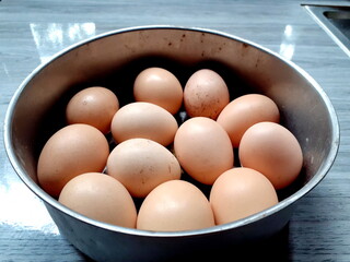 Close-up raw chicken egg group in a stainless steel bowl, and isolated on blue background, cooking...