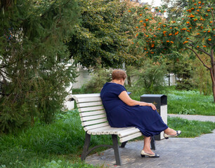Fototapeta premium A woman is sitting with a phone on a park bench.