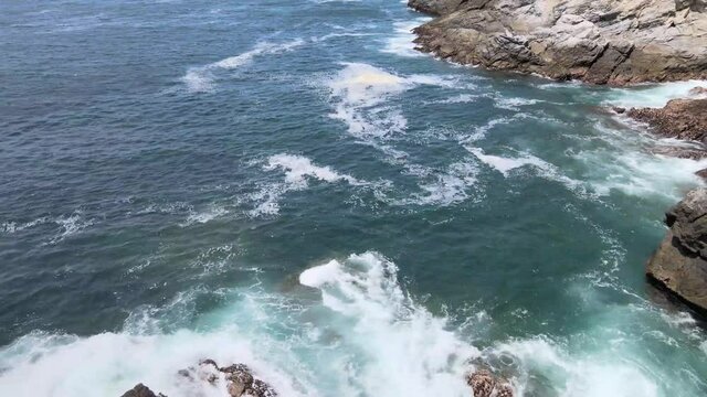 Pull back above rocks and waves in Oaxaca, Mexico