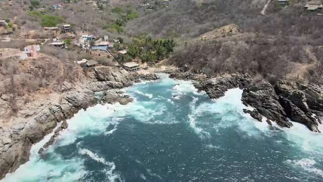 Pull back above small beach, with view of cliffs in Oaxaca, Mexico
