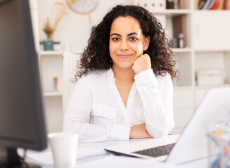 Confident young woman posing in office of international company