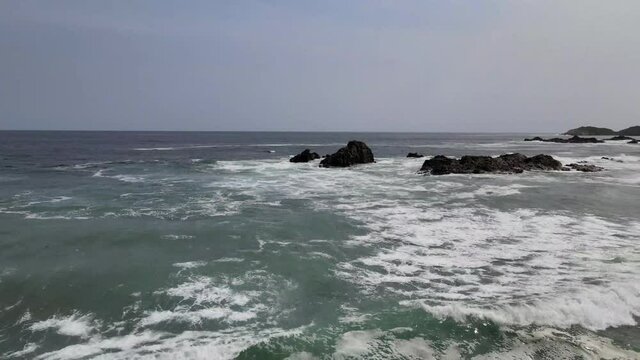 Flying above waves with view of rocks in Mazunte, Oaxaca, Mexico