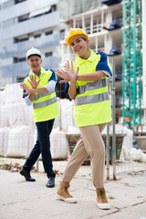 Funny smiling builders man and woman dancing at construction site