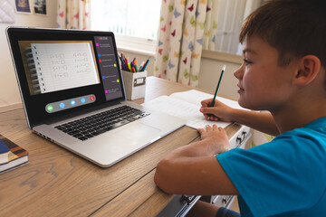 Fototapeta na wymiar Caucasian boy using laptop for video call, with class on screen