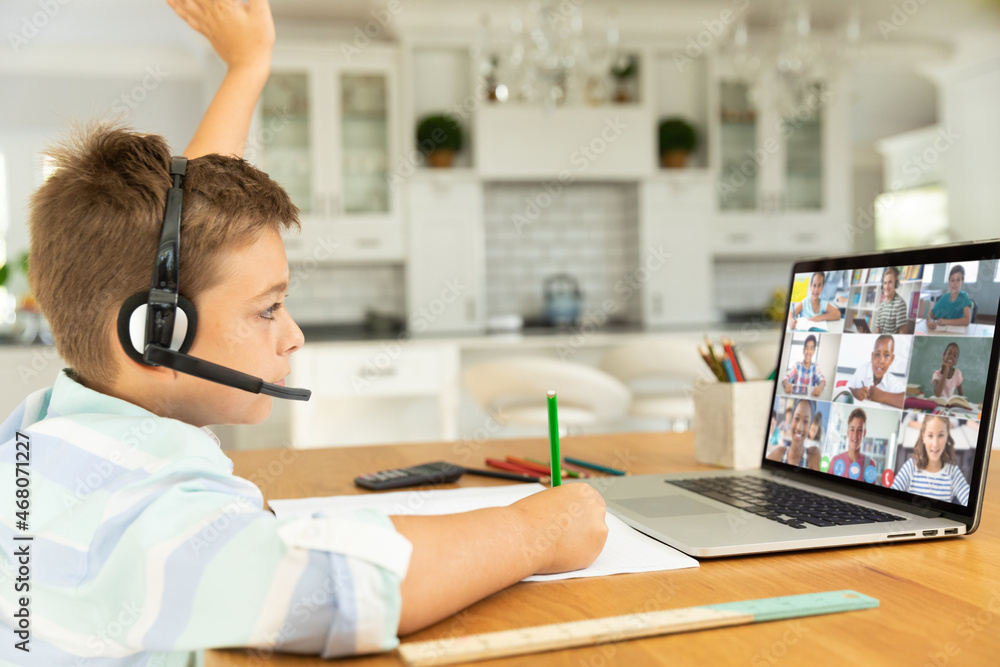 Canvas Prints Caucasian boy raising hand for video call, with smiling diverse elementary school pupils on screen