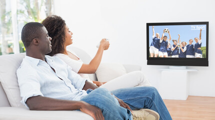 Rear view of african american couple sitting at home together watching football match on tv