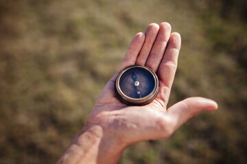 Hiking hand holding classic compass on natural background