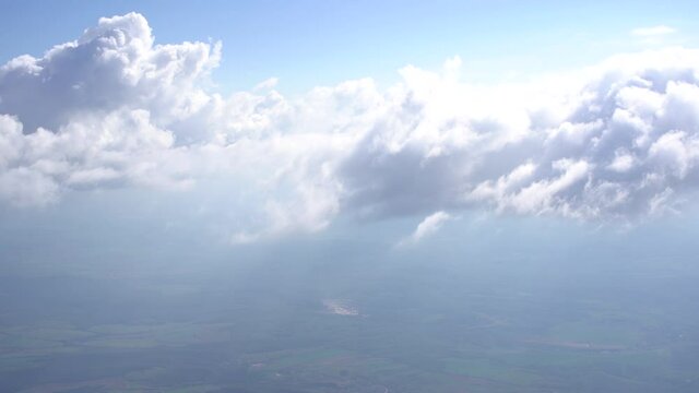 View of the white clouds above the ground from the airplane window