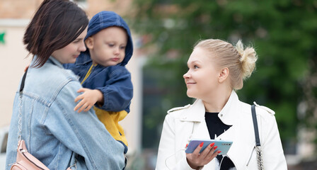 A girl walking around the city met a friend with a child