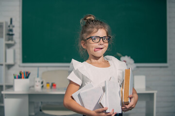 Cute funny child with tongue studying in classroom at elementary school. Elementary school and primary education.