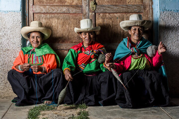 Mujeres andinas latinoamericanas, sentadas, tejiendo lana y sonriendo felices - obrazy, fototapety, plakaty