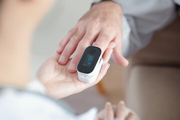 Doctor helping patient to put on pulse oximeter device for checking oxygen saturation