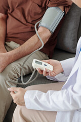 Fototapeta na wymiar General practitioner using electronic tonometer when checking blood pressure of senior patient