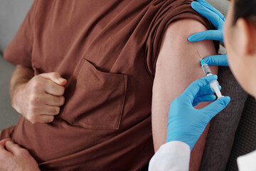 Close-up image of man getting vaccine against coronavirus in his shoulder