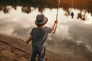 Child fishing near lake in summer