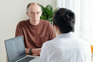 Serious senior man visiting doctor to discuss his complaints and disease symptoms