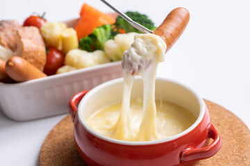 チーズホンデュとカラフルな蒸し野菜　
 パーティー料理が並ぶ白いテーブル