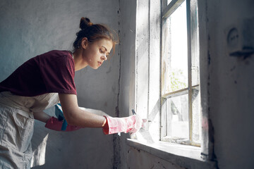 Fototapeta na wymiar woman painter paints window with brush renovation interior decoration