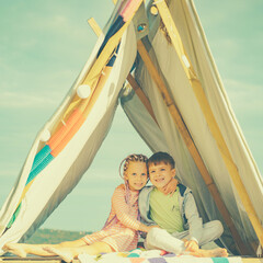 Obraz premium Kids in homemade tent. Best friends spend time together. Laughing brother and sister playing together. Outdoor vacation.