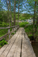 Obraz premium Wooden bridge, in summer in a mountain chalet, crossing a small river in retro style.