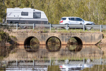 Car and caravan driving across culverts under a road, Durras Lake, NSW, October 2021 - obrazy, fototapety, plakaty