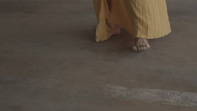 African American woman in yellow dress standing barefoot dancing slowly. Conceptual and methaphoric estabilized footage