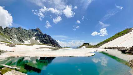 alpine lake with snow and reflection in rocky mountain
