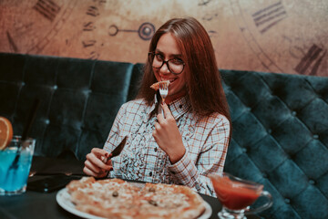 A business woman on a lunch break eating pizza in a modern restaurant. Selective Focus