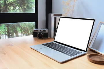 Fototapeta premium Laptop computer with blank screen, camera and books on wooden table.