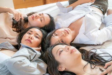 Obraz na płótnie Canvas Happy joyful young women friend taking gossip lying on bed looking to camera