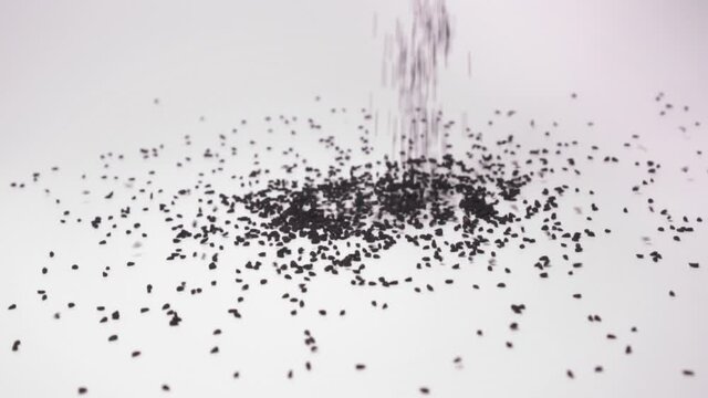 Close up of Nigella Sativa Falling On White Background - slow motion