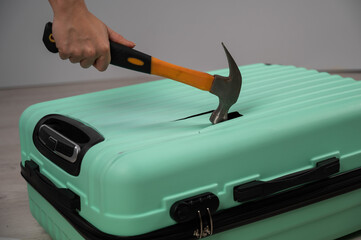 A woman hits a suitcase with a hammer on a white background.