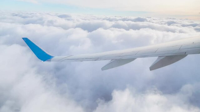 Wing of an airplane flying above the clouds. Looks at the sky from the window of the plane, using airtransport to travel
