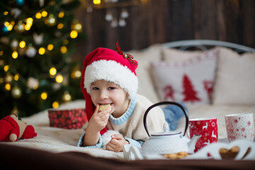 Cute toddler child, boy in a christmas outfut, playing in a wooden cabin on Christmas, derocation around him