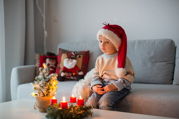 Cute toddler child, boy in a christmas outfut, playing in a wooden cabin on Christmas, derocation...