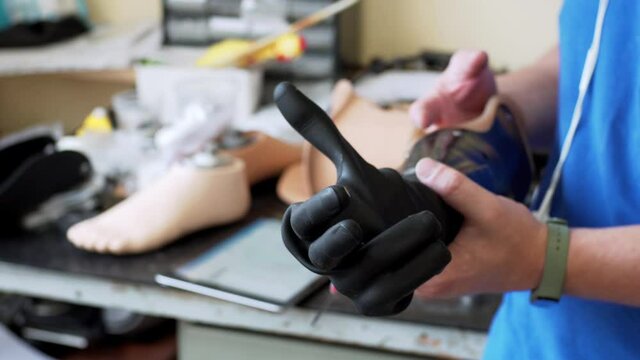 A medical prothetics techinican demonstrates the black modern artifical bionic arm prothesis moving its fingers. An artificial hand moves black fingers in the laboratory 