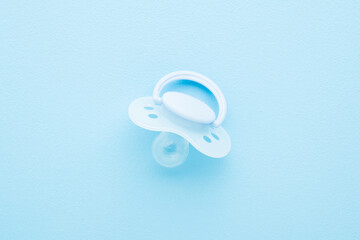 New silicone baby soother on light blue table background. Pastel color. First newborn toy. Closeup. Top down view.