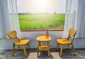 The open windows let the sunlight into the room where tables and chairs with vases of flowers were placed.