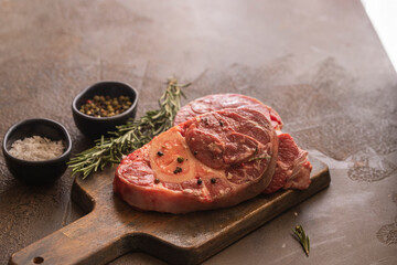 Osso bucco beef fillet on wooden cut board on concrete table ready for cooking