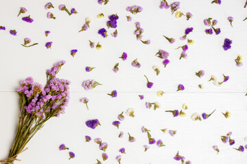 Colorful flowers leaves and set of purple flowers over the white wooden background. 