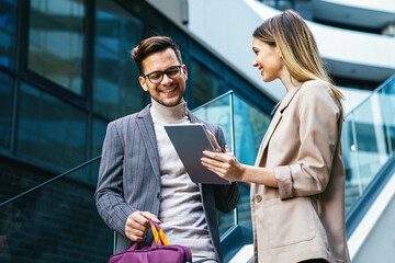 Successful young business people talking, working together in front of modern business building